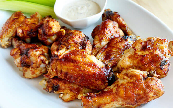 bbq wings, celery sticks, and dip on a plate