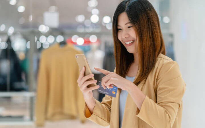 asian woman looking at phone in retail store