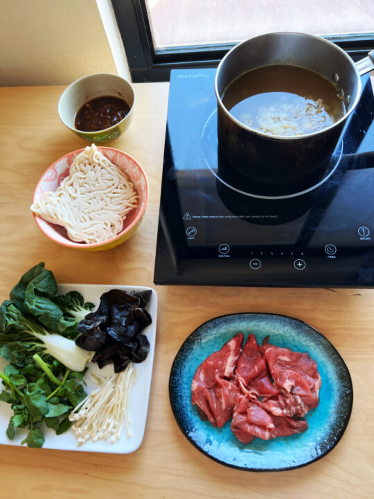 Pot with soup on an induction stove and side dishes