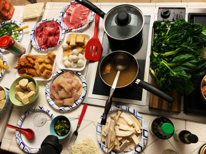 Hot Pot soup in pot and meat and side dishes on a kitchen island