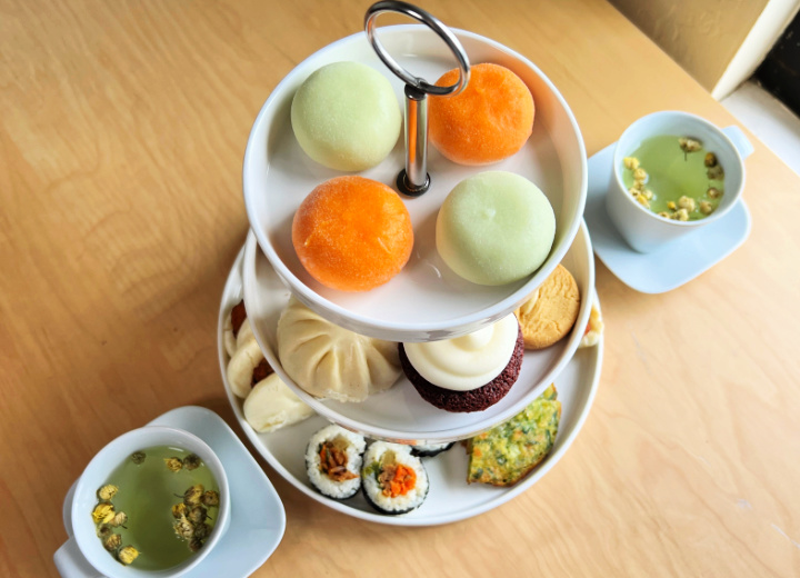 afternoon tea stand with asian food items and 2 cups of tea